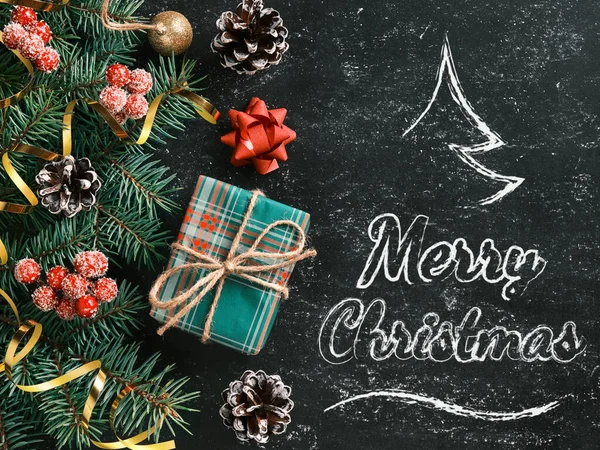 Fondo de Navidad con un estilizado árbol de Navidad y letras de Feliz Navidad en una pizarra. Composición de Año Nuevo con una caja de regalo y otras decoraciones navideñas — Foto de Stock