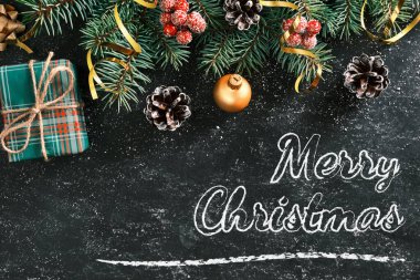 Noel arkaplanda bir yazı tahtasında Mutlu Noeller yazısı var. Hediye kutusu ve diğer Noel süslemeleri olan yeni yıl kompozisyonu