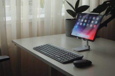 Tablet cihazı ve klavyesi olan şık bir iş yeri. Minimalizm iç mimarisi