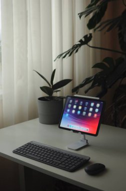 Tablet cihazlı ev ofisi. Minimalizm tarzı iç mekan. İçinde bitkiler olan modern iç mekan..