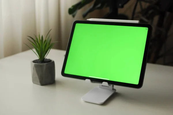 Tableta sobre soporte con fondo verde. Minimalismo interior con plantas de interior —  Fotos de Stock