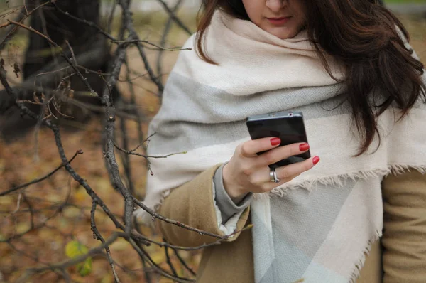 Girl is texting in her phone outside in winter time. Online speaking — Stock Photo, Image