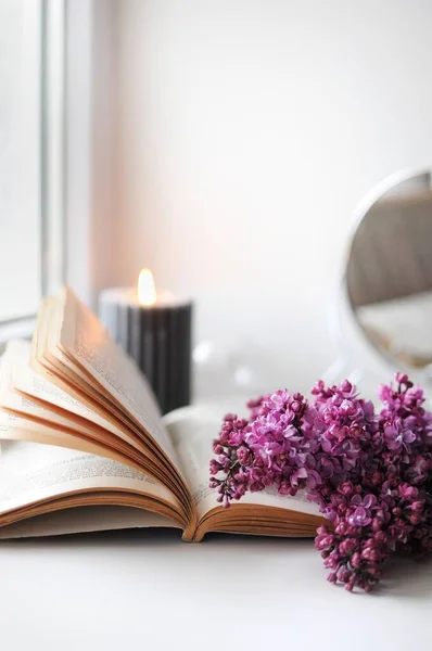 Spring flatlay at home with lilac, book and candle. Season blooming time. — Fotografia de Stock