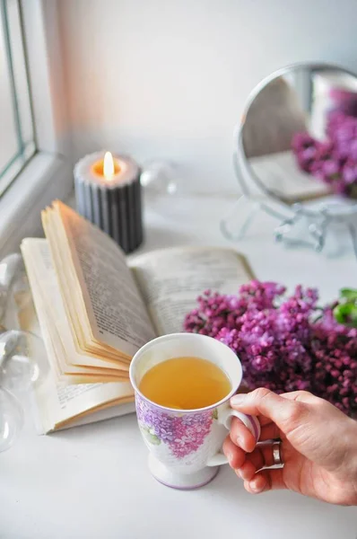Livro aberto com um arbusto lilás. Aconchegante atmosfera caseira romântica com uma vela. — Fotografia de Stock