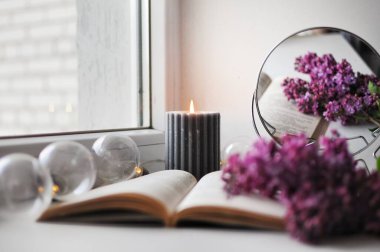 Romantik bir köşesi var. Açık bir kitap, mum ve leylak çalısı var..