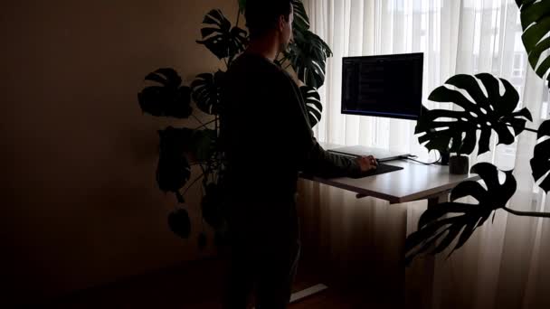 一个年轻人站在那里在笔记本电脑上工作。从家庭内部进行的工作 — 图库视频影像