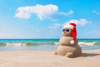 Noel Baba şapkalı kumlu plajda yılbaşı kardan adam