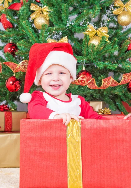 Criança sorridente com chapéu de Papai Noel na caixa de presente — Fotografia de Stock