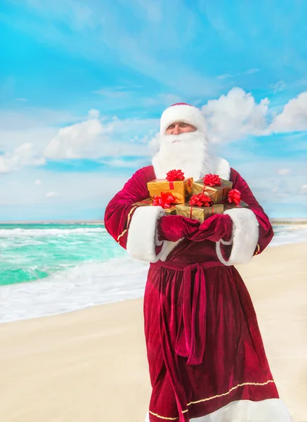 Santa Claus con regalos en la playa de mar — Foto de Stock