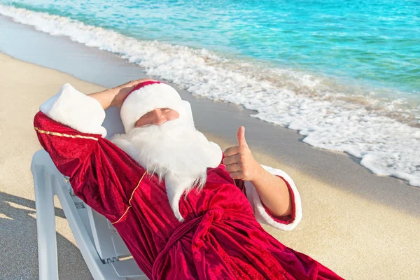 Weihnachtsmänner ruhen sich in Chaiselongue am Strand aus — Stockfoto