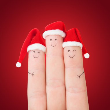 Noel Baba şapkaları kırmızı bir arka plan karşı parmak yüzleri
