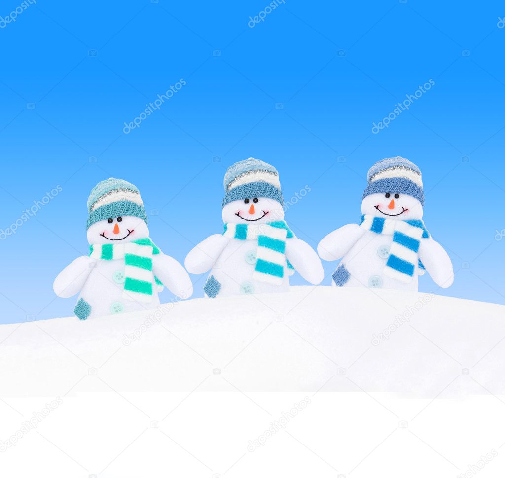 Winter snowmen family against blue sky