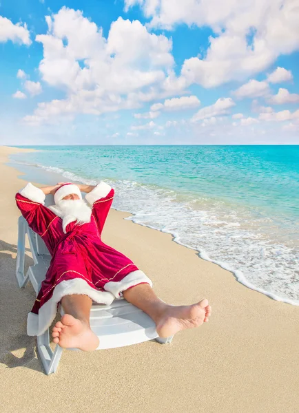 Santa Claus je nutný odpočinek v chaise longue na mořské pláži — Stock fotografie