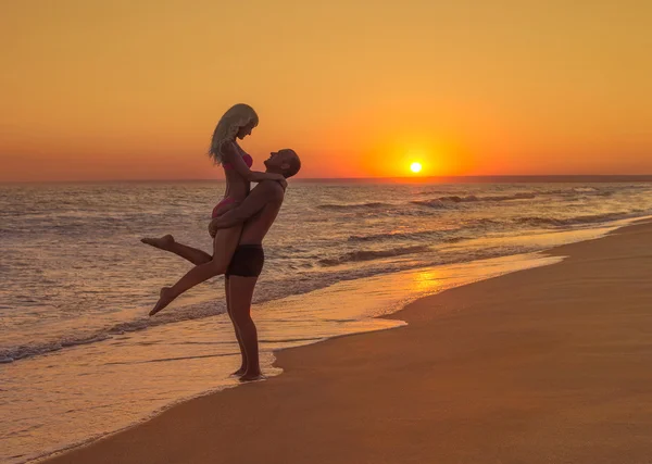 Milující pár na pláži při západu slunce — Stock fotografie