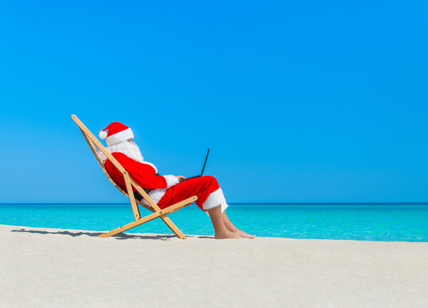 Santa Claus at beach using laptop