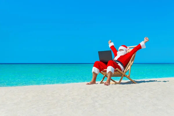 Άγιος Βασίλης στην παραλία χρησιμοποιώντας φορητό υπολογιστή — Φωτογραφία Αρχείου
