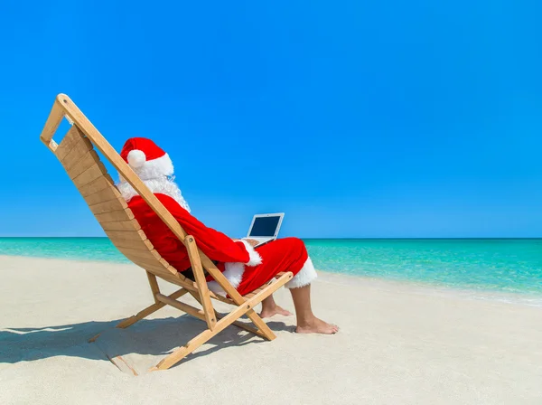 Santa Claus vid stranden med laptop — Stockfoto