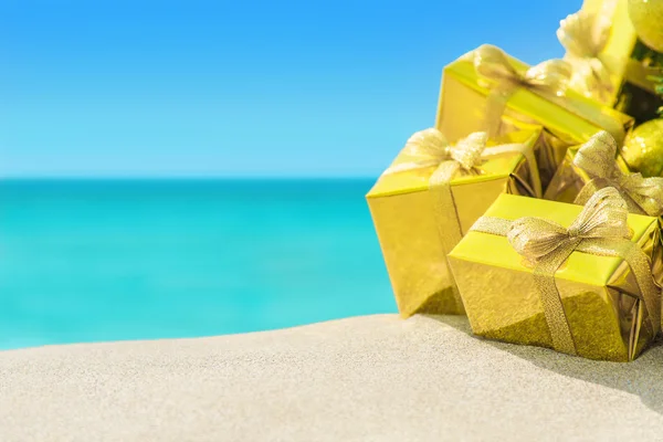 Golden gift boxes on beach — Stock Photo, Image
