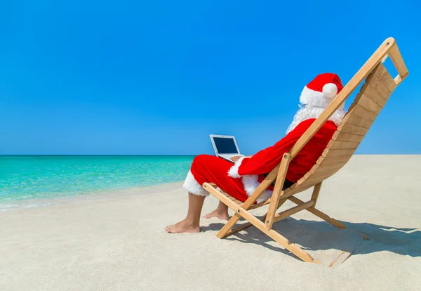 Santa Claus vid stranden med laptop — Stockfoto