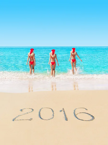 Women in red Christmas hats on beach — Stock Photo, Image