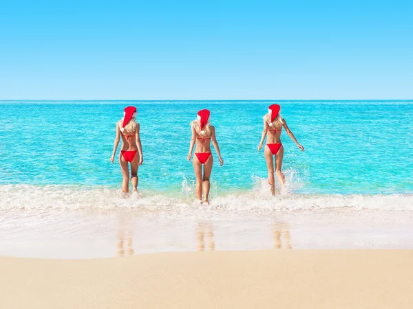 Kvinnor i röda jul hattar på stranden — Stockfoto