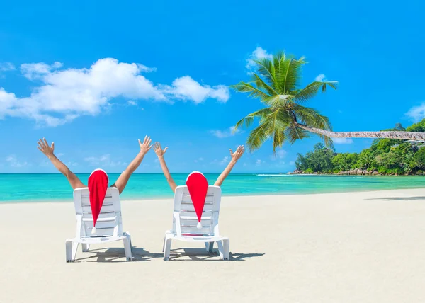 Romantiska par i santa hattar på stranden — Stockfoto