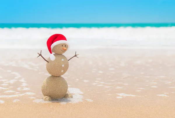 Sandy Noel kardan adam Noel Baba şapkası okyanus plaj kum, içinde — Stok fotoğraf