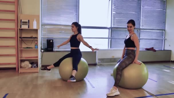 Gimnasio Dos Chicas Están Sentadas Bolas Fitness Tratando Mantener Equilibrio — Vídeos de Stock