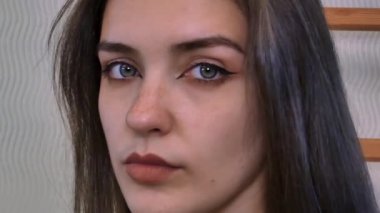 Çekici genç bayanın çilli yüzü. Sakince ve güvenli bir şekilde bakıyor ve arkasını dönüyor. Yakın plan..