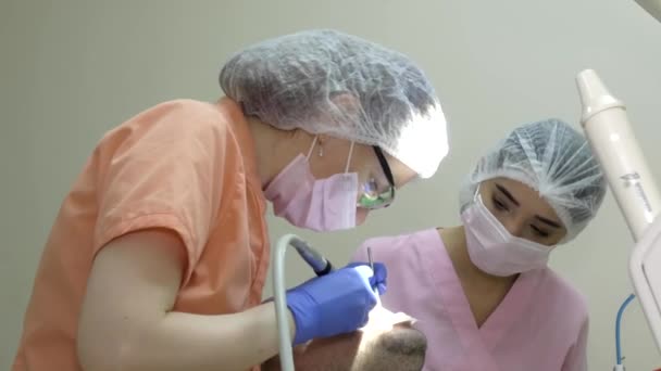 Uma Mulher Dentista Trata Paciente Por Perto Uma Jovem Assistente — Vídeo de Stock