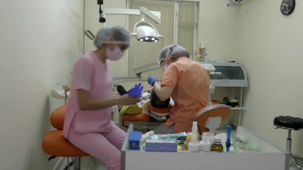 Assistente Dentista Jovem Senta Uma Cadeira Coloca Luvas Nas Proximidades — Vídeo de Stock