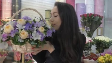 Güzel bir çiçekçi elinde bir sepet çiçek tutar ve hayran kalır..