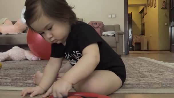 孩子坐在房间的地毯上玩玩具 用手指按着什么东西 — 图库视频影像