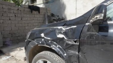 Terk edilmiş bir bölgeye park edilen kazadan sonra sol çamurluğu ezilmiş siyah bir araba..