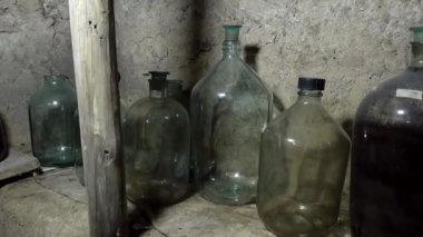 Büyük cam şarap şişeleri. Eski bir toprak şarap mahzeninde boş ve dolu duruyor..