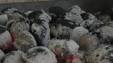 Kömür tutuştu. Kalıplı kömür parçaları tutuşturuluyor. Bazı kömürler zaten açık kül tabakasıyla kaplıdır, bazıları daha yeni yanmaya başlamıştır. Yakın plan..
