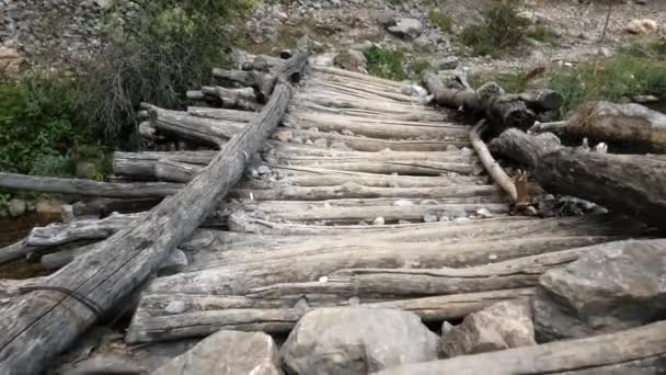 Uma velha passarela de madeira sobre um rio de montanha. A câmera se move sobre a ponte — Vídeo de Stock