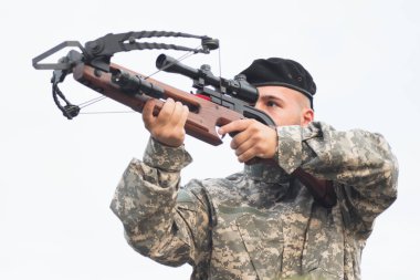Askeri üniformalı asker yaylı tüfeği nişan alıyor ve ateş ediyor..
