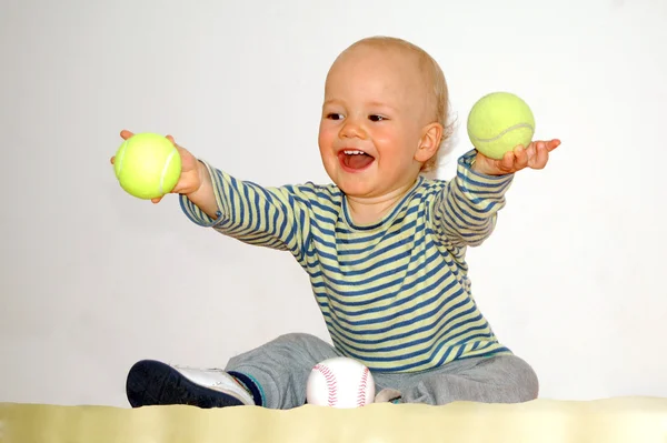 Szczęśliwe dziecko bawi się piłki tenisowe — Zdjęcie stockowe