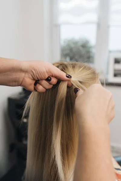 Girl in a hair salon, stylist make hair style for client in Woman\'s Hair In Hairdresser Salon, close view of hands, spikelet