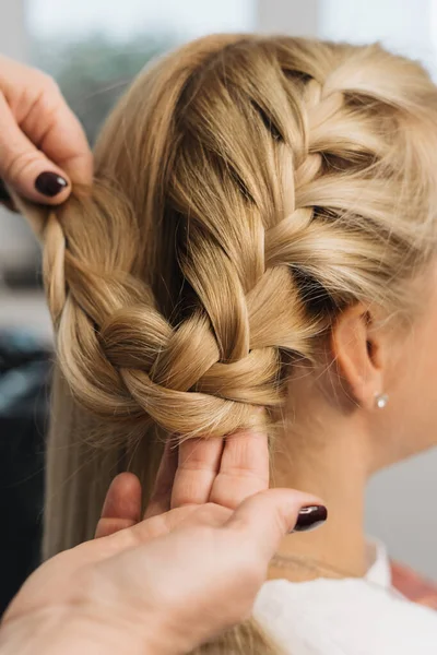 Girl in a hair salon, stylist make hair style for client in Woman\'s Hair In Hairdresser Salon, close view of hands, spikelet