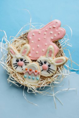 Paskalya yumurtaları ve tavşanlar, mavi arka planda jöleli kurabiyeler.