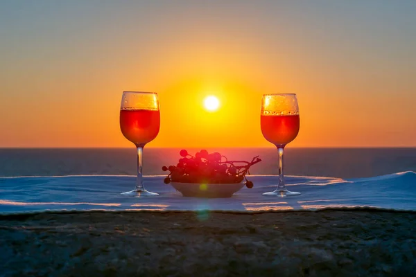 Two glasses of wine and grapes at sea sunset, Sicily island, Italy