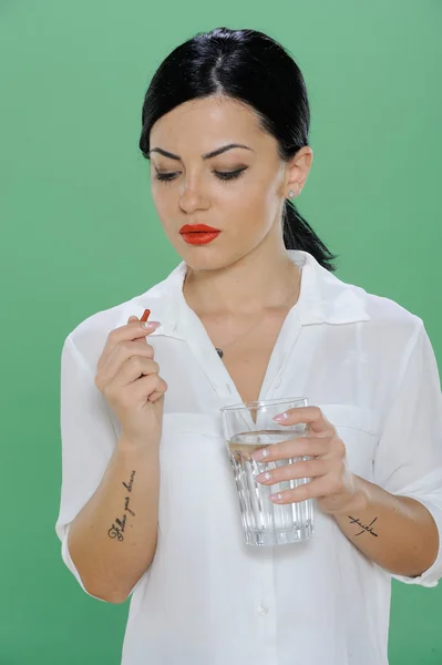 Vrouw met een pil en een glas water in de hand — Stockfoto