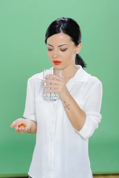 Mulher segurando uma pílula e um copo de água na mão — Fotografia de Stock