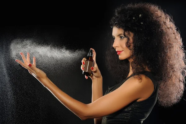 Een portret van een mooie vrouw parfum spuiten op zwarte pagina Stockafbeelding