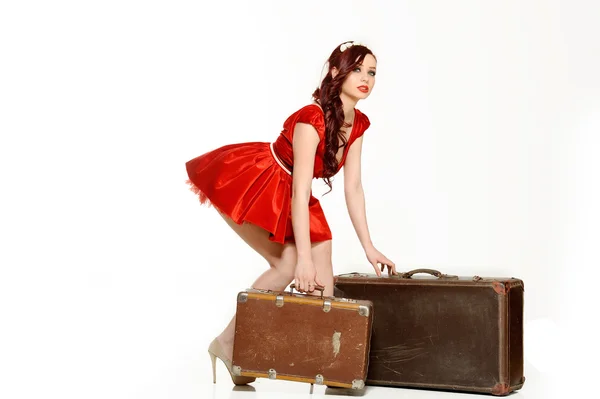Schöne Frau in einem roten Kleid mit Retro-Koffer posiert auf weißem Hintergrund — Stockfoto