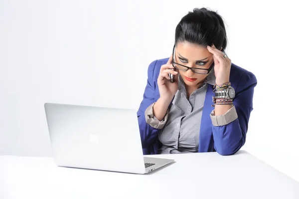 Mooie jonge vrouw zit op Bureau en praten op mobiele telefoon geïsoleerd op witte achtergrond — Stockfoto