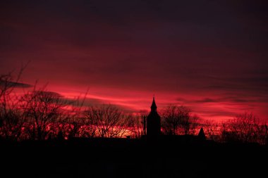 Kırmızı günbatımı gökyüzü ve kırmızı bir kilisenin silüeti.