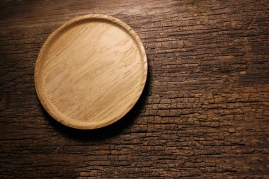 Eski masanın üzerinde yuvarlak ahşap bir tabak. Metin için üst görünüm kopyalama alanı. Yemek ve menü geçmişi